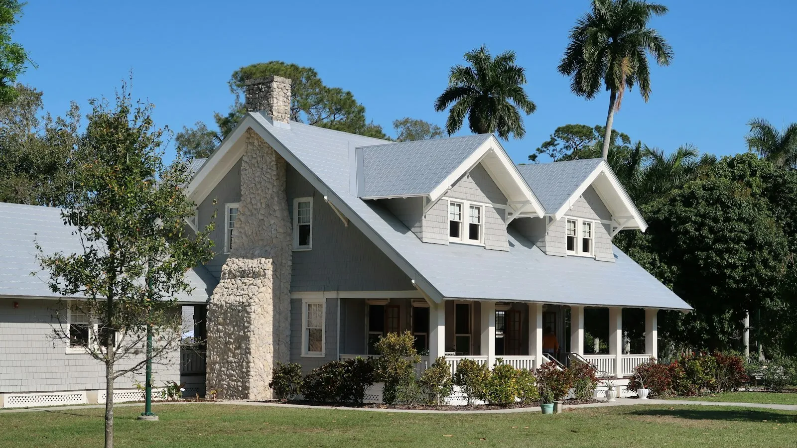 Florida home with dormers and a wide front porch under royal palms