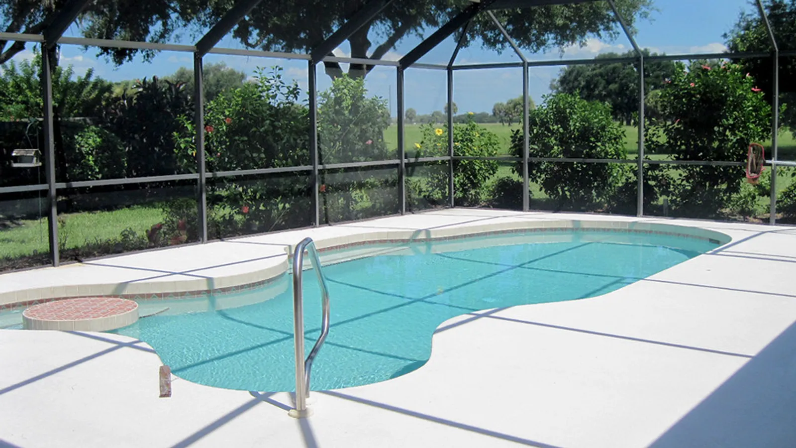 Covered outdoor lounge and dining space beside a pool at a white Florida home